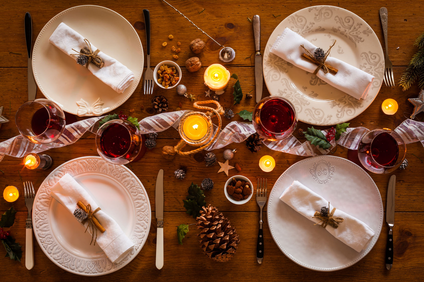 Christmas table setting for family dinner at a cosy rustic table with candles and decorations. Top view.